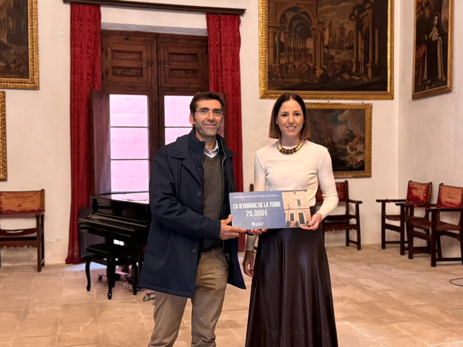 La consejera de Cultura y Patrimonio, Antònia Roca, entrega la subvención al representante de Ca n'Horrac de la Torre.